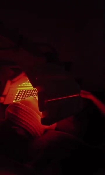 Medilux LED light therapy panel glowing red over a client's face
